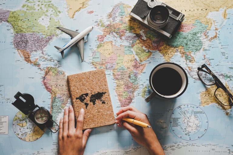 Top view of young woman planning her vacation using world map - Travel influencer looking for the next travel destination - Concept of adventure, tourism, and traveling people lifestyle